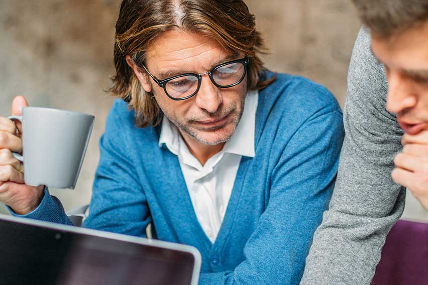 2 people standing over a computer talking