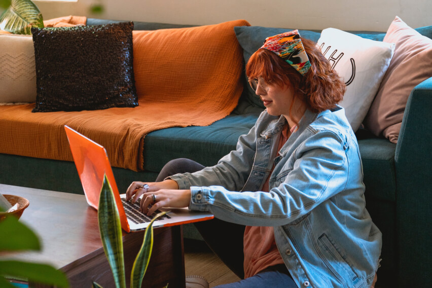 woman sitting on floor working on laptop at home