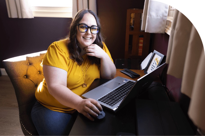 Lindsay Darby, CMA, smiling at camera, seated, with laptop