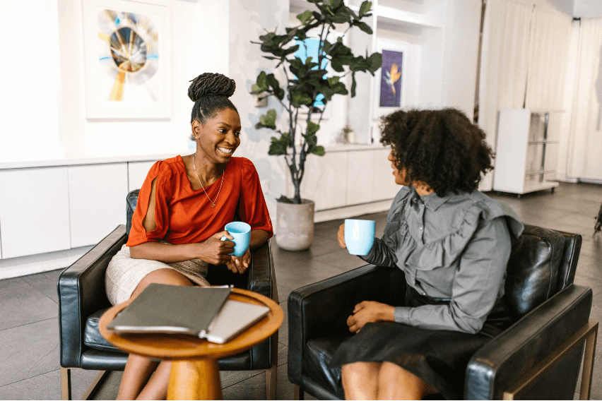 Two professional-looking women sitting together smiling and talking