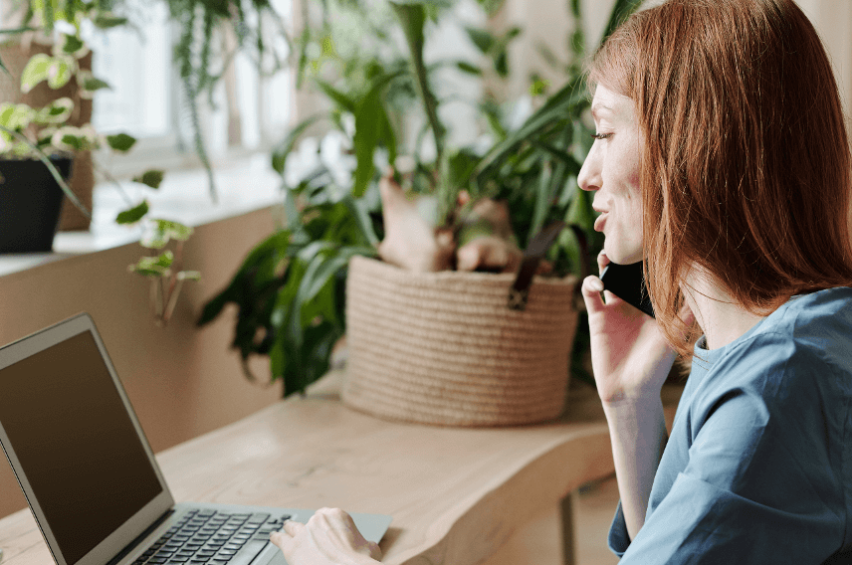 woman on phone looking at laptop