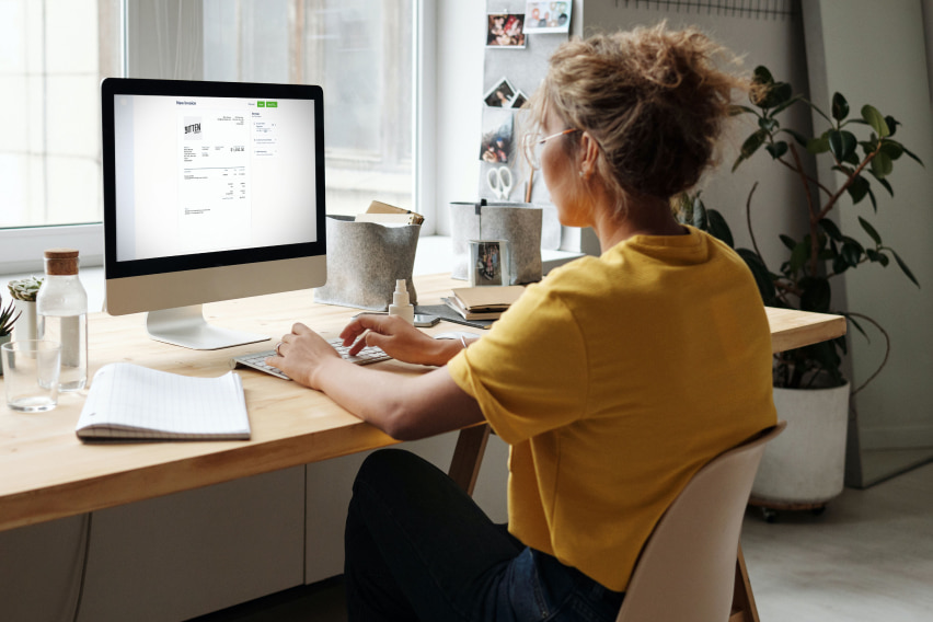 woman at computer looking at business invoice