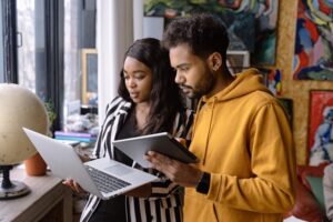 colleagues standing side by side looking at laptop and tablet